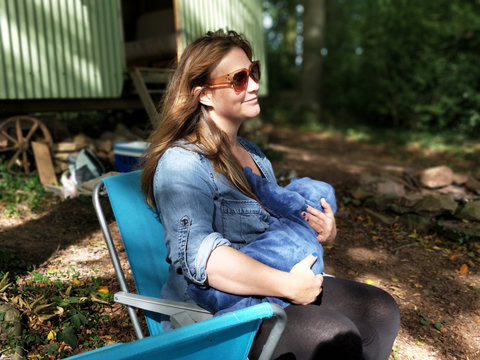 Woman with sunglasses holding baby outside on a camping chair