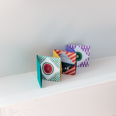 A multicolored and patterned origami concertina miniature photo album, displayed on a white background in a photo taken by NiMi Projects for its origami workshops.