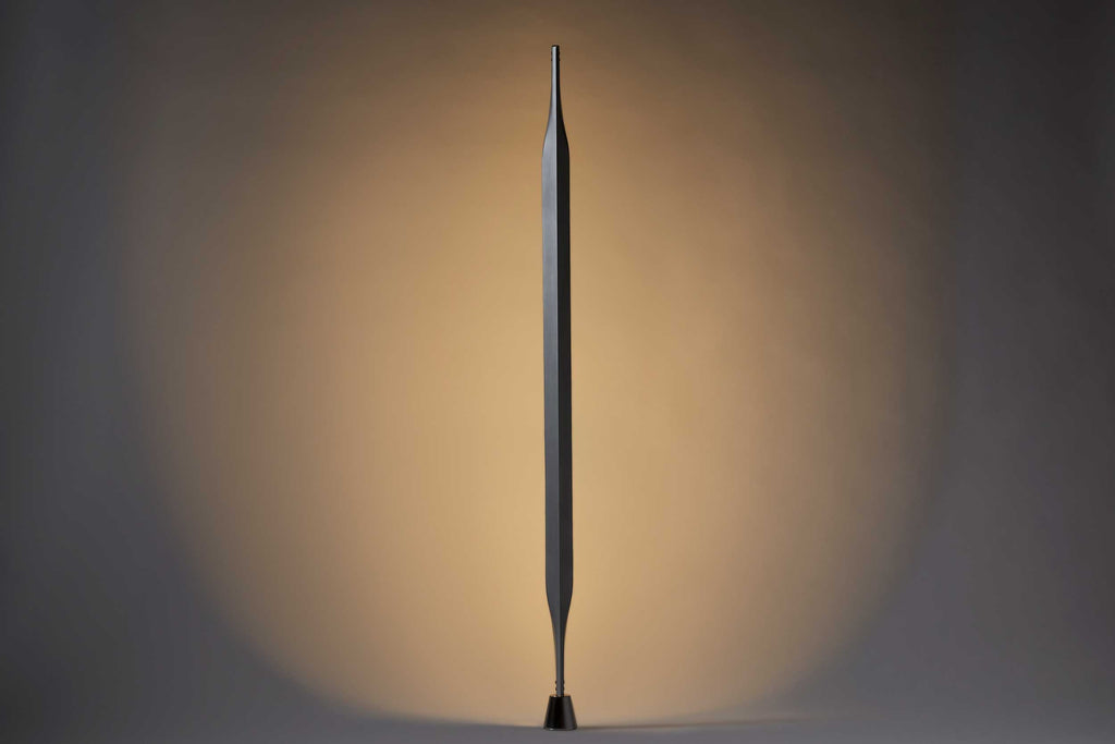 Kodai Iwamoto's Arrow Lamp, an elongated arrow-shaped indirect light lamp in dark aluminum.