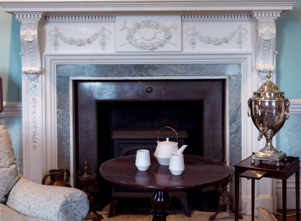 A pink Frustum Japanese teapot with matching cups on an antique coffee table at Chiddingstone Castle, for the  NiMi Projects popup exhibition\