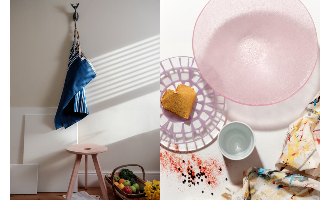 A composite of two images: Left shows a blue and white canvas and cotton Sanpu Sanyo Sanpu apron hanging on a hook above a pink Atelier Yocto three-legged wooden Flower Stool. Right shows two Saburo hand-crafted glass bowls, one with a window pattern, the other frosted. All items are handmade in Japan,  and images shot at NiMi Projects UK.  