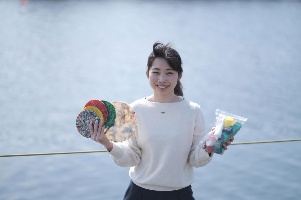 Sayumi Tadokoro, cheif designer of Buoy recycled plastic homeware for Techno-Lab, holds up a few samples of different coloured items made from recycled marine waste plastic collected from the shores of Japan.