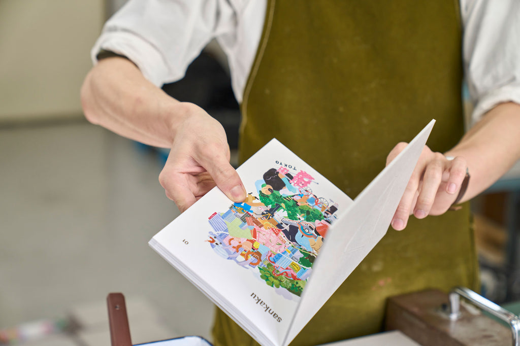 An employee of Shinohara Shiko, a book binders in Tokyo, checking a copy of sankaku Vol. 1, a book featuring interviews with artisans and creative people based in Tokyo, Japan.