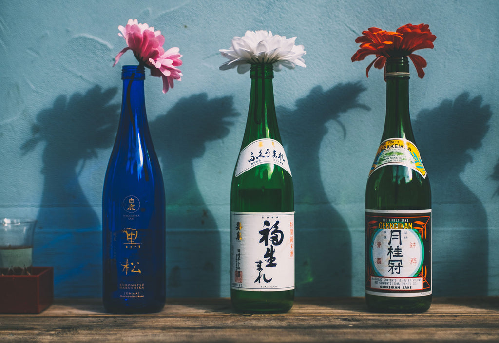 Three bottles of sake, each with a flower inside.