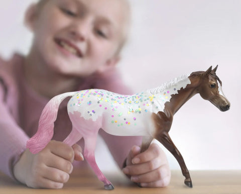 Little girl playing with Breyer's Freedom/Classic Series model horse, Neapolitan, who's decorated like the popular ice cream treat that he's named for.