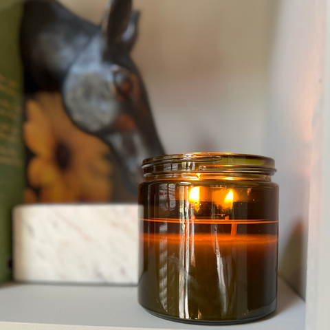 aged green candle jar on grey shelf with horse head decor