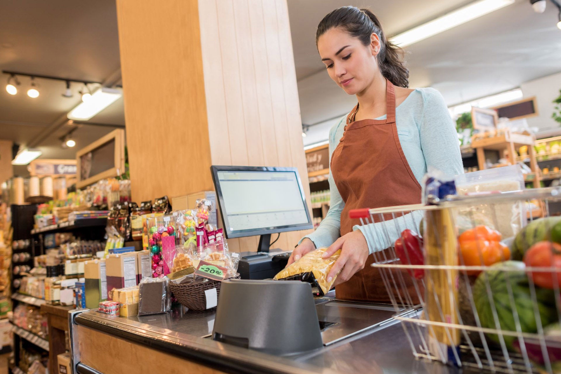 A cashier scanning grocery items at a supermarket counter