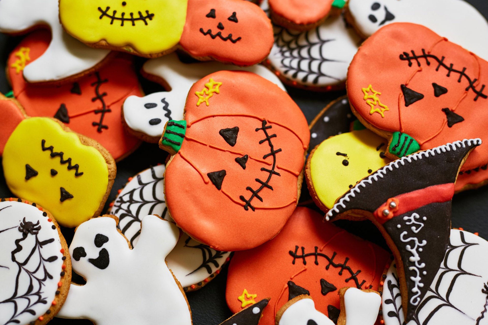 An assortment of Halloween sugar cookies in the form of pumpkins, spiderwebs, and ghosts