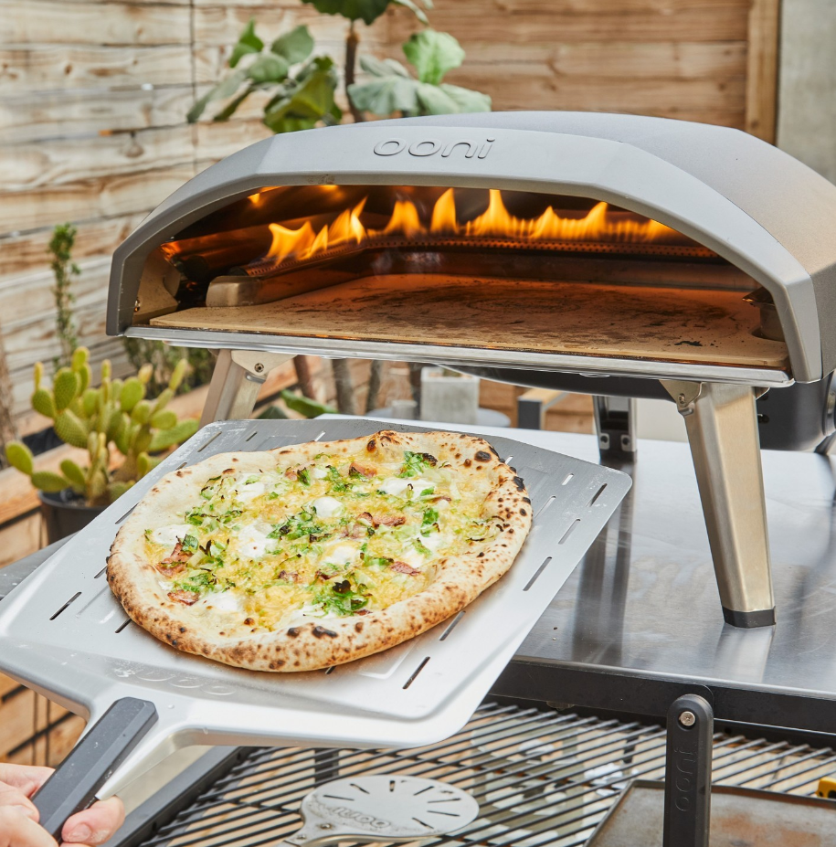 A pan pizza being taken out of an Ooni oven