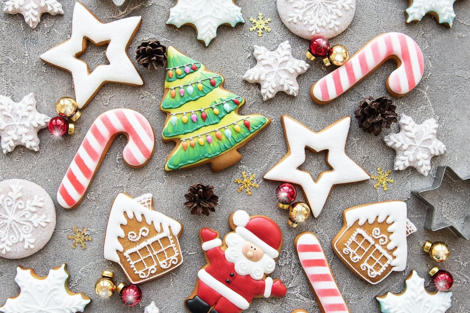 cookies in the shape of Santa Claus, candy canes, stars, and gingerbread houses spread out on a table