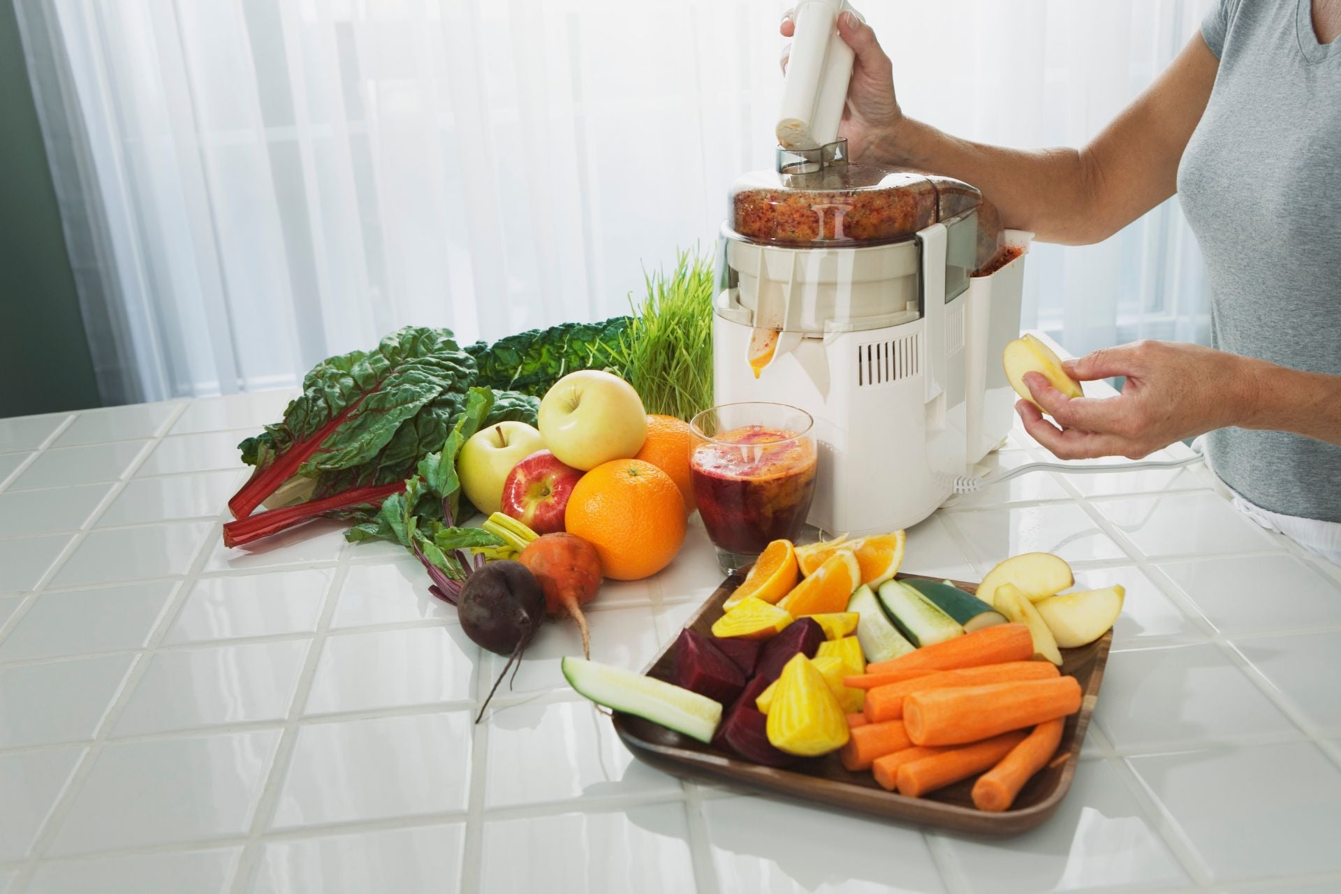 A woman holds an apple while operating the juicer