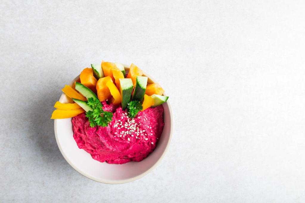 Beetroot Hummus with carrots, cucumbers, parsley, and sesame seeds