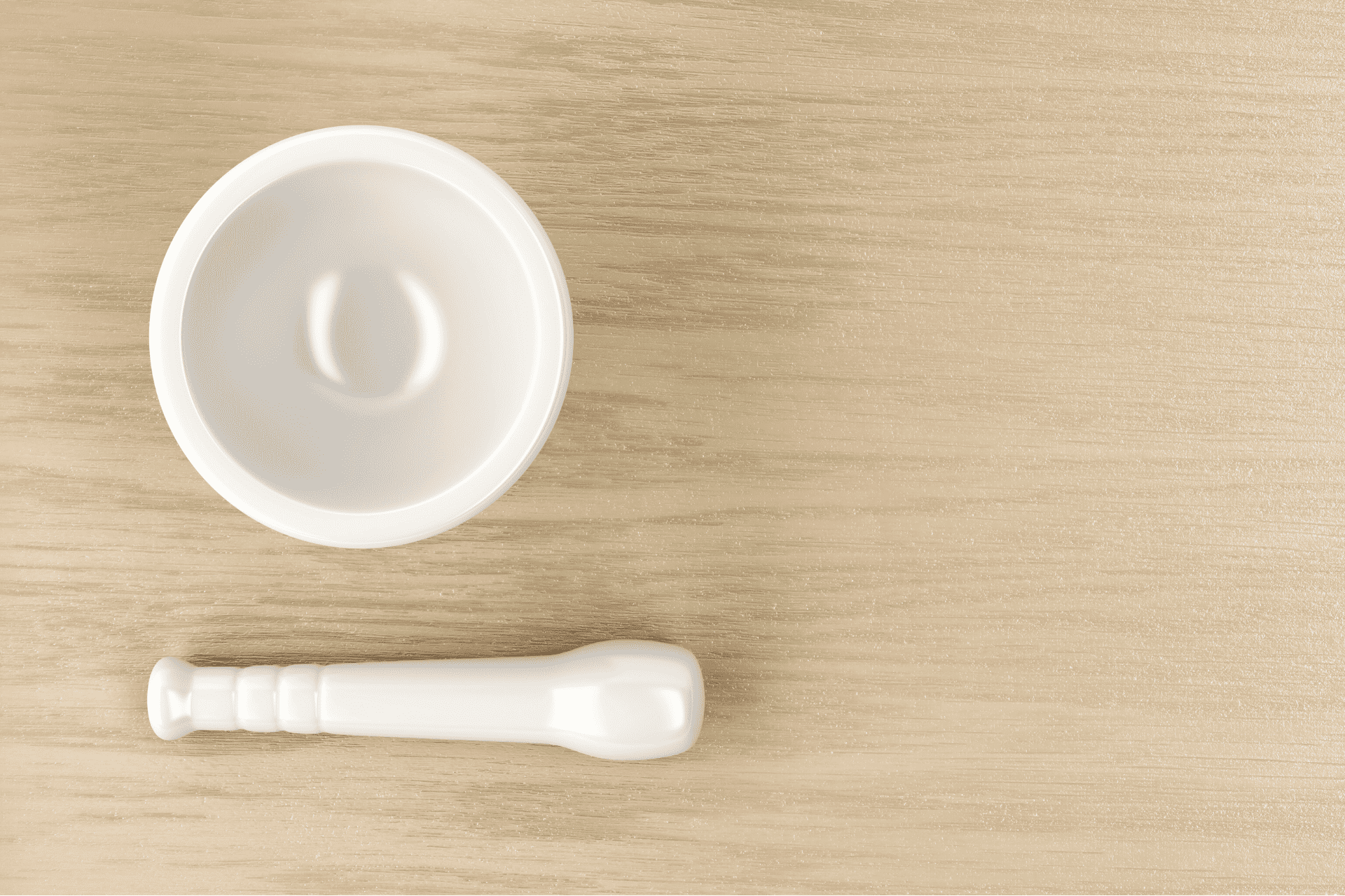 A ceramic mortar and pestle laid out on a wooden table