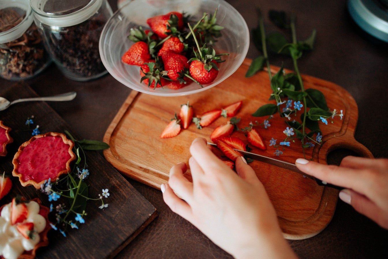 a woman cuts strawberries with an essential kitchen knife