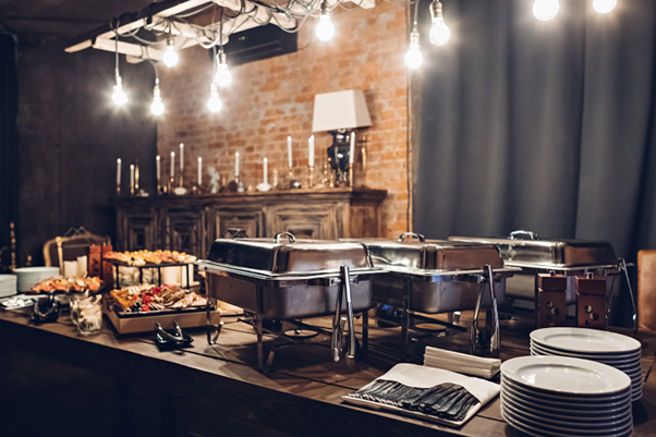 three chafers filled with hot barbecued food next to cold appetizers at an event venue