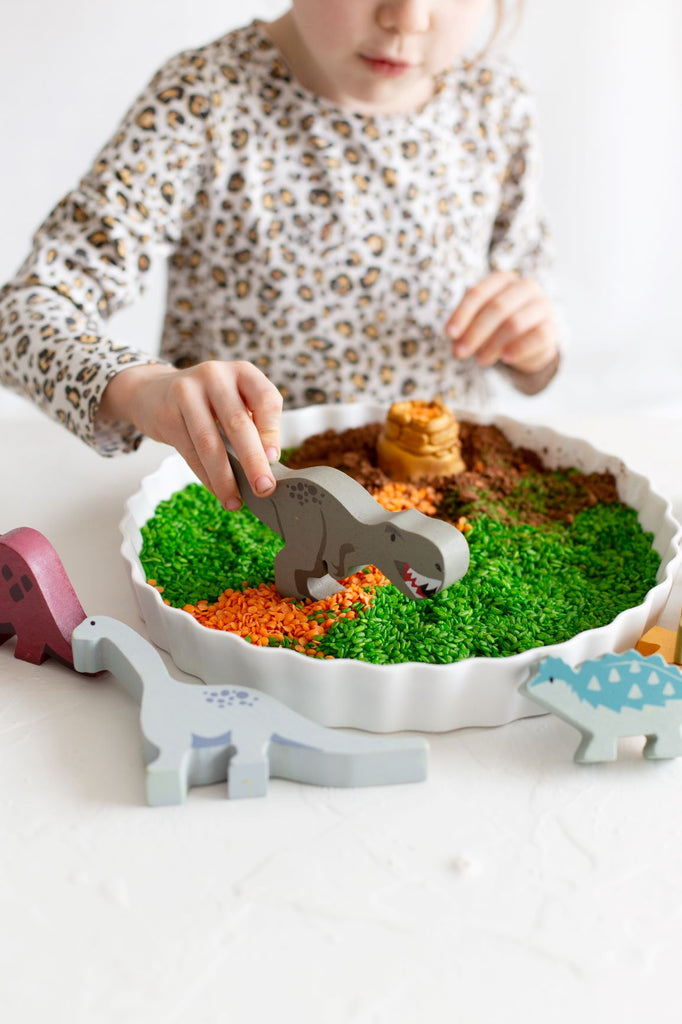 DIY Creative Play - Dinosaur FIMO fun with wooden dinosaur toys in a baking tray with coloured rice