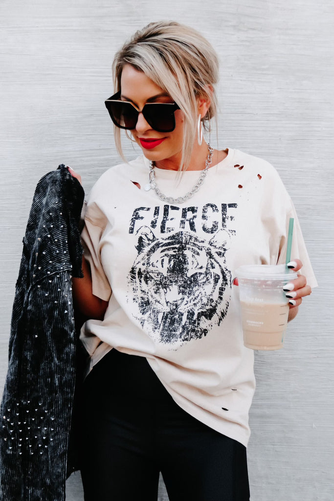 woman with her blonde hair pulled back wearing a white distressed t-shirt with a lion and the word "fierce" on it from the A-List Boutique in Nebraska