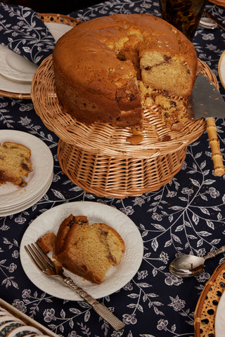 Chocolate chip coffee cake on wicker cake stand and blue tablecloth