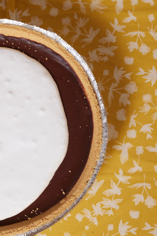 Partial view of chocolate meringue pie on yellow tablecloth