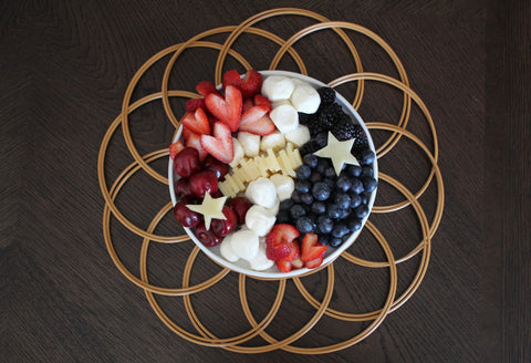 red white and blue cheeseboard with heart shaped strawberries and cheese stars on hoop charger and dark wood table