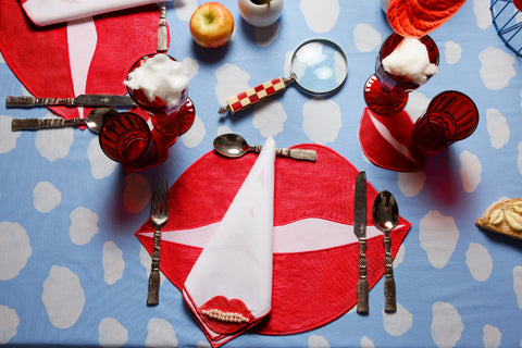 Place setting with red lips and clouds for a surrealist dinner party