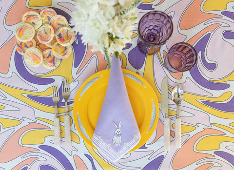 place setting with pastel colored table linens, glassware, and flatware for Easter