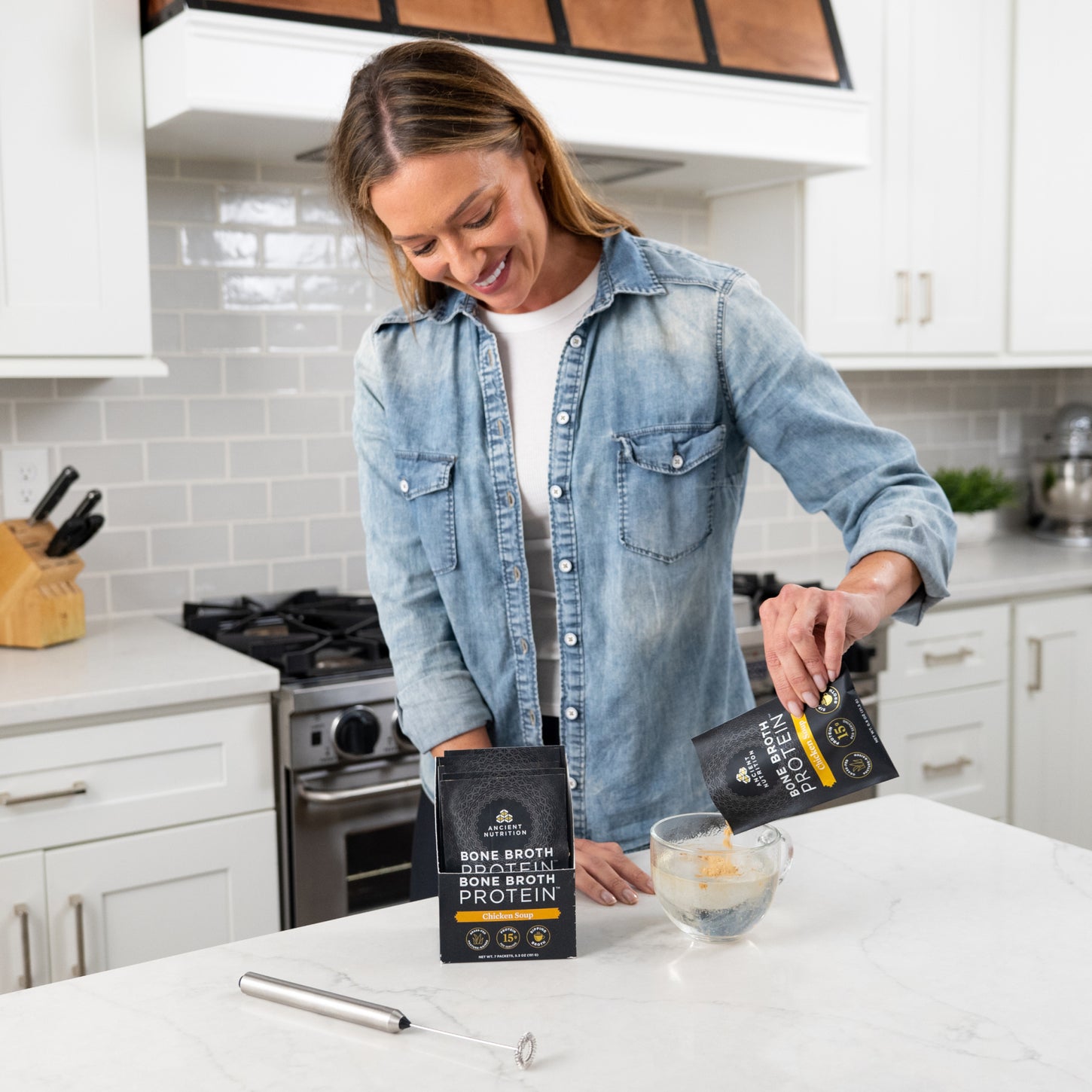 woman pouring a packet of bone broth protein chicken soup in a clear mug of water