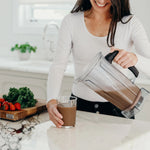 girl pouring smoothie in a glass cup