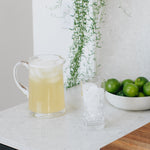 pitcher of cucumber lime collagen next to bowl of limes