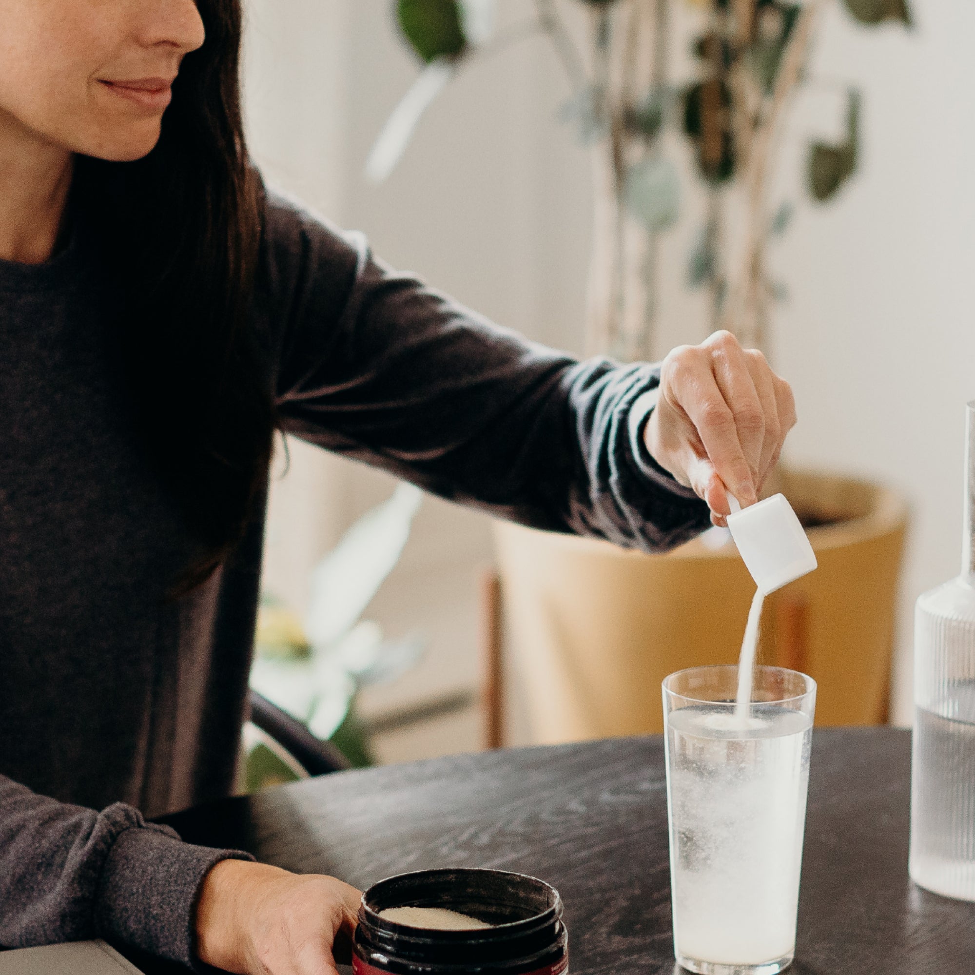 women pouring scoop of cucumber lime collagen in a glass