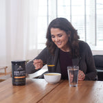 woman at a table eating bone broth with a spoon