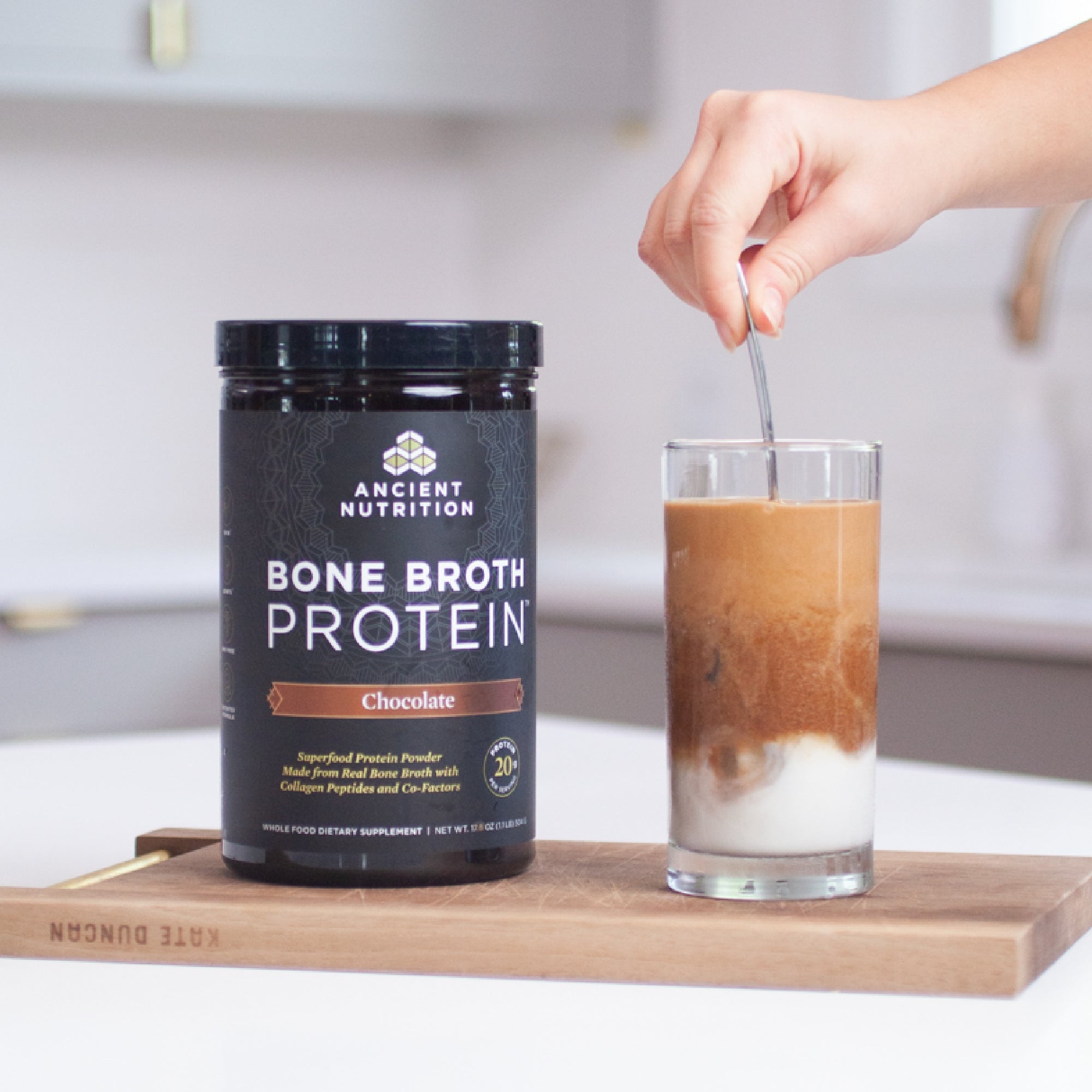 person stirring bone broth protein chocolate in oat milk