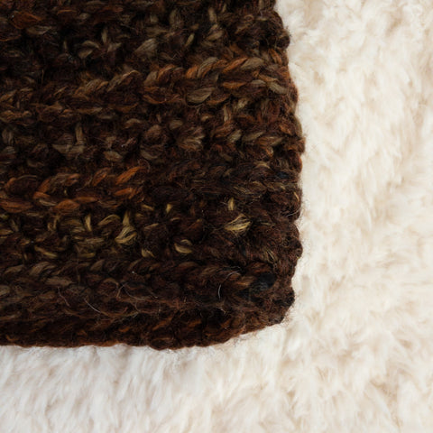 Close up of the lower right edge of a deep brown speckled crocheted beanie