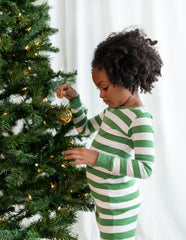 Child decorating the Christmas tree in cozy pajamas