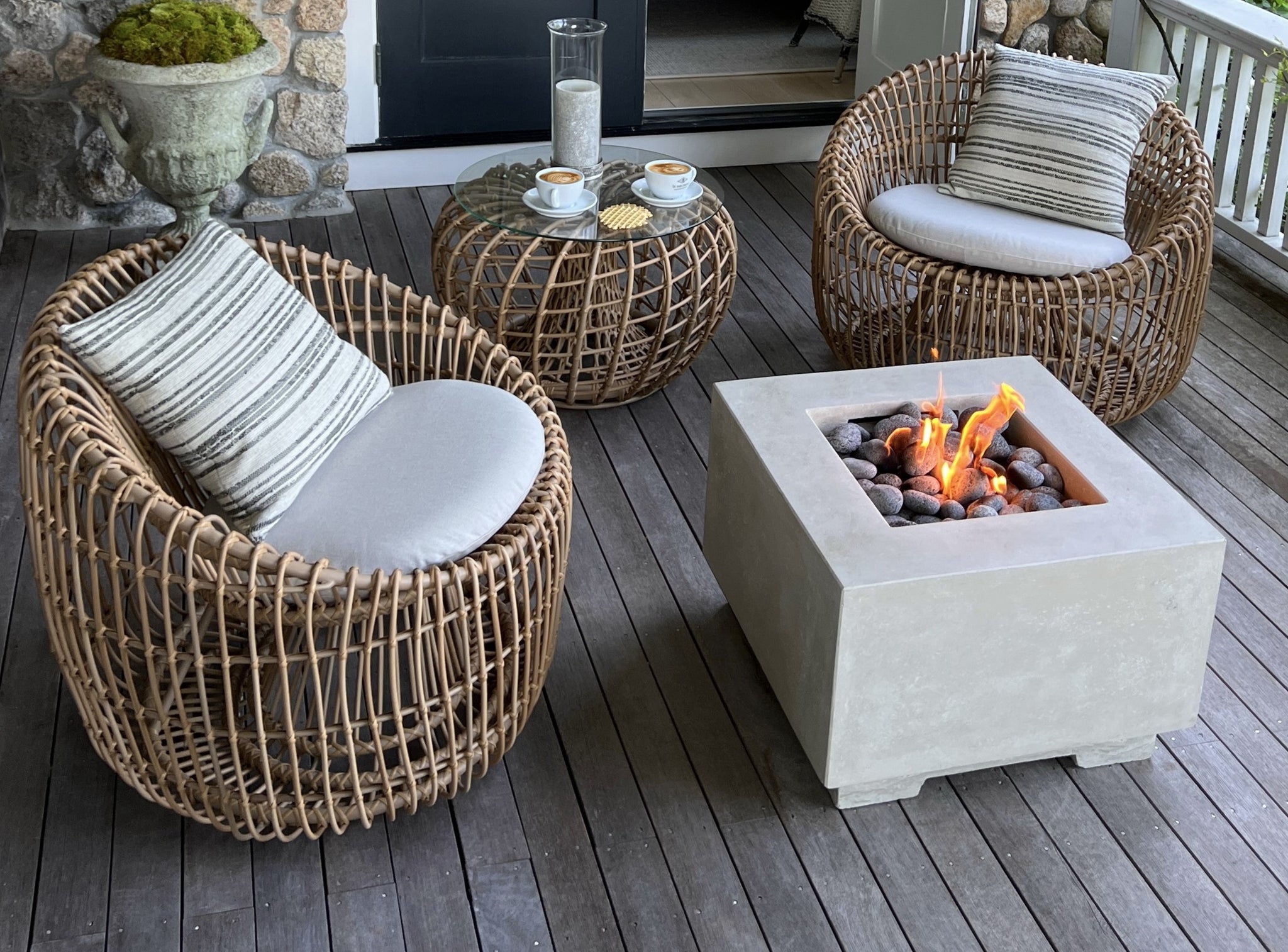 Outdoor lounge on veranda with round rattan look a like material, wicker patter, two round chairs and a side table with glass table top