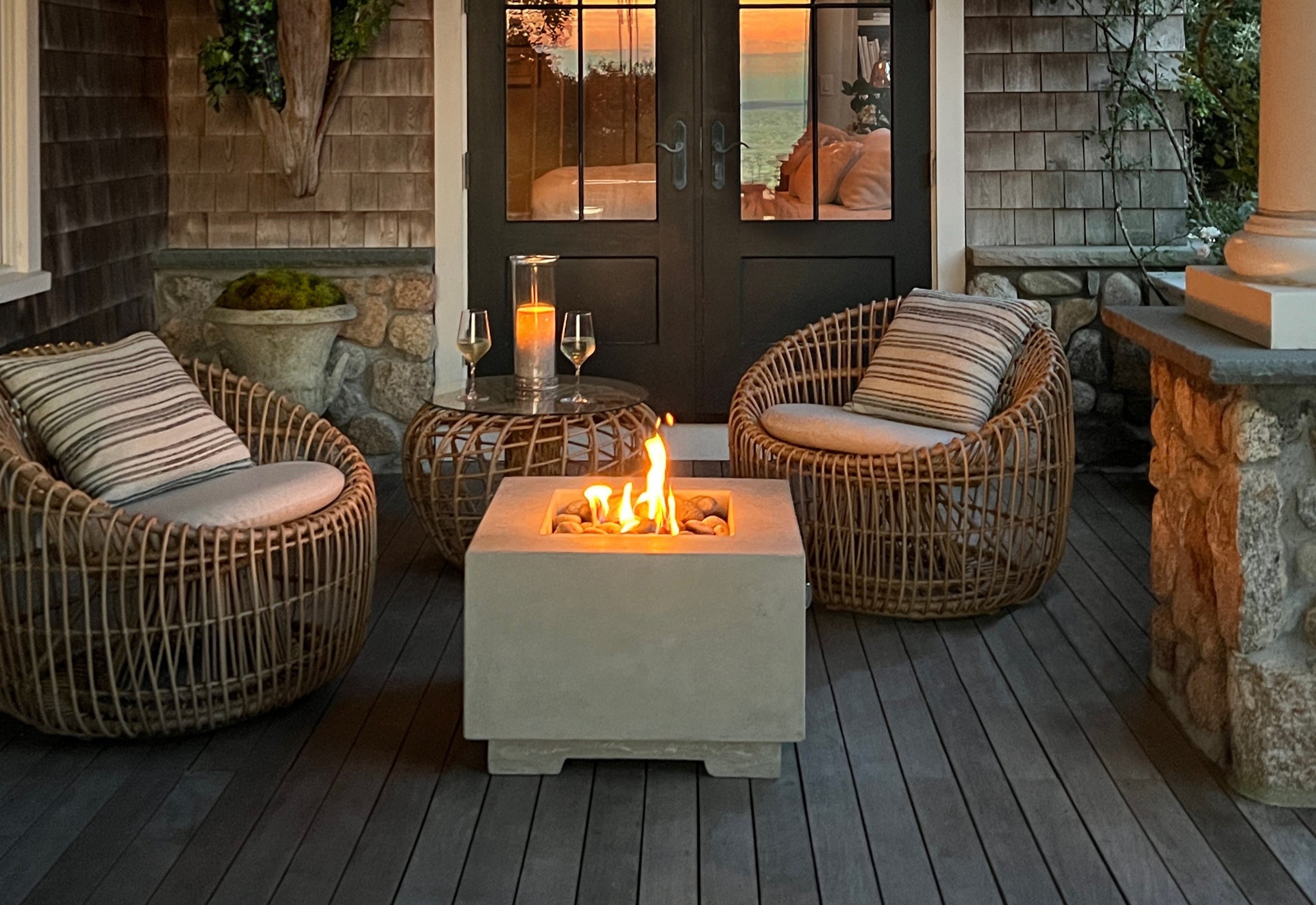 Outdoor lounge with two Nest round chairs and Nest side table with glass table top, sunset evening, liten candlelight, two wines glass with white wine