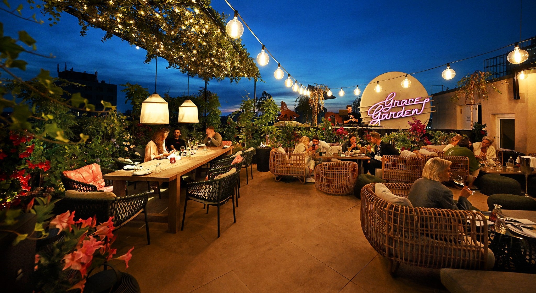 Evening vibes at Grace Garden bar and lounge terrace, people having a drink or glass of wine, cosy outdoor light chains