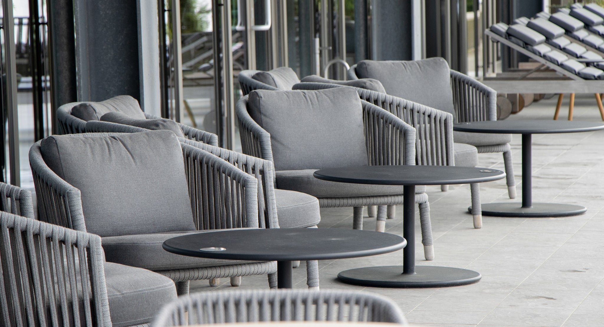 Grey Cane-line Moments lounge chairs at Alsik Norcid Spa & Wellness outdoor terrace with black round coffee tables