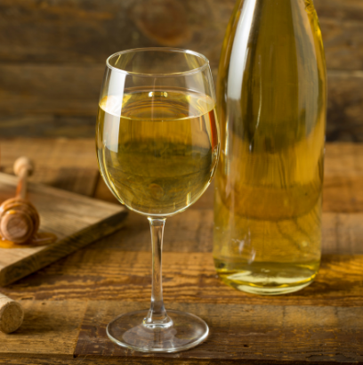 glass and bottle of mead on a wooden table