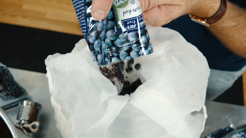 adding freeze dried blueberries to a mesh bag