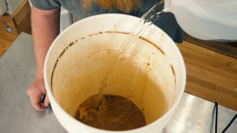 pouring distilled water onto the yeast cake at the bottom of a fermenter