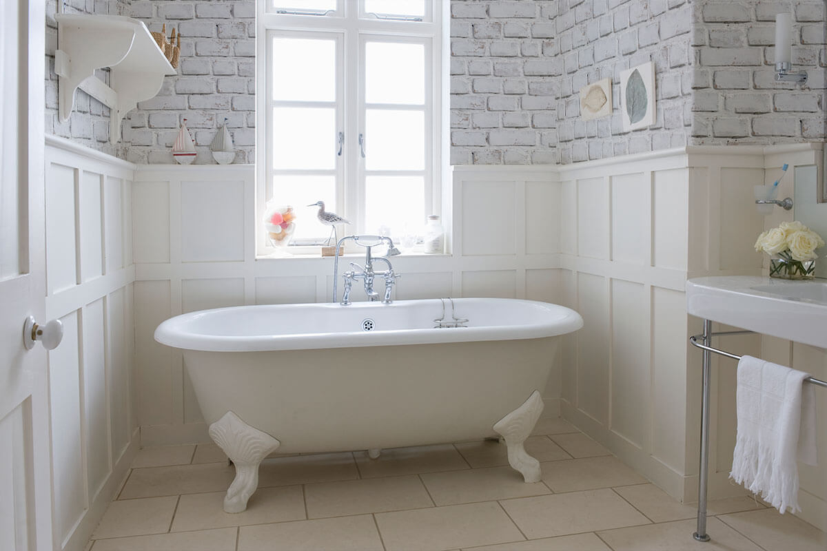 A classic bathtub with brick removable wallpaper in the background