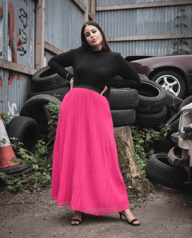 model in bright pink skirt and black high neck top 