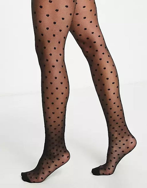 a models legs shown wearing the ASOS Design polka dot tights in black 