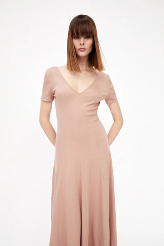 a woman pictured wearing a dusty pink coral v-neck dress.