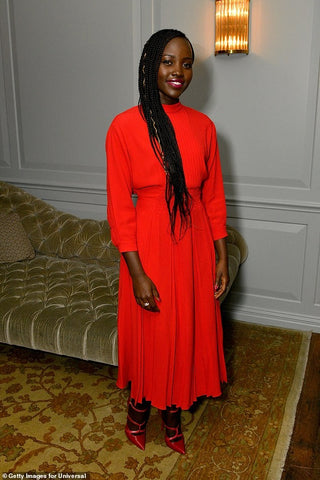 lupita nyong'o bright red long sleeved dress at an event.