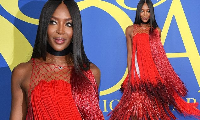 Naomi Campbell pictured at a event wearing a colourful red flared dress.