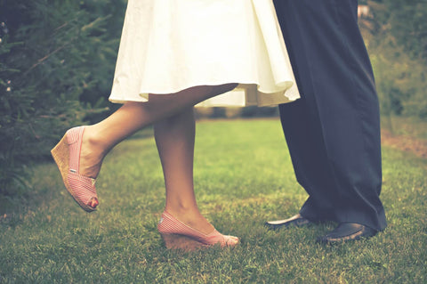 Couple standing in grass, wedges, white dress 