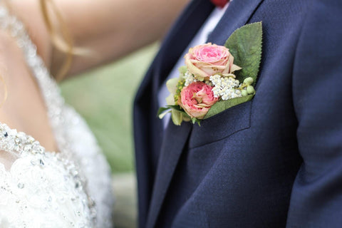 bride and groom standing close together, groom with buttonhole flowers in jacket 