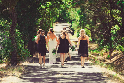bride and bridesmaids walk down road, black dresses